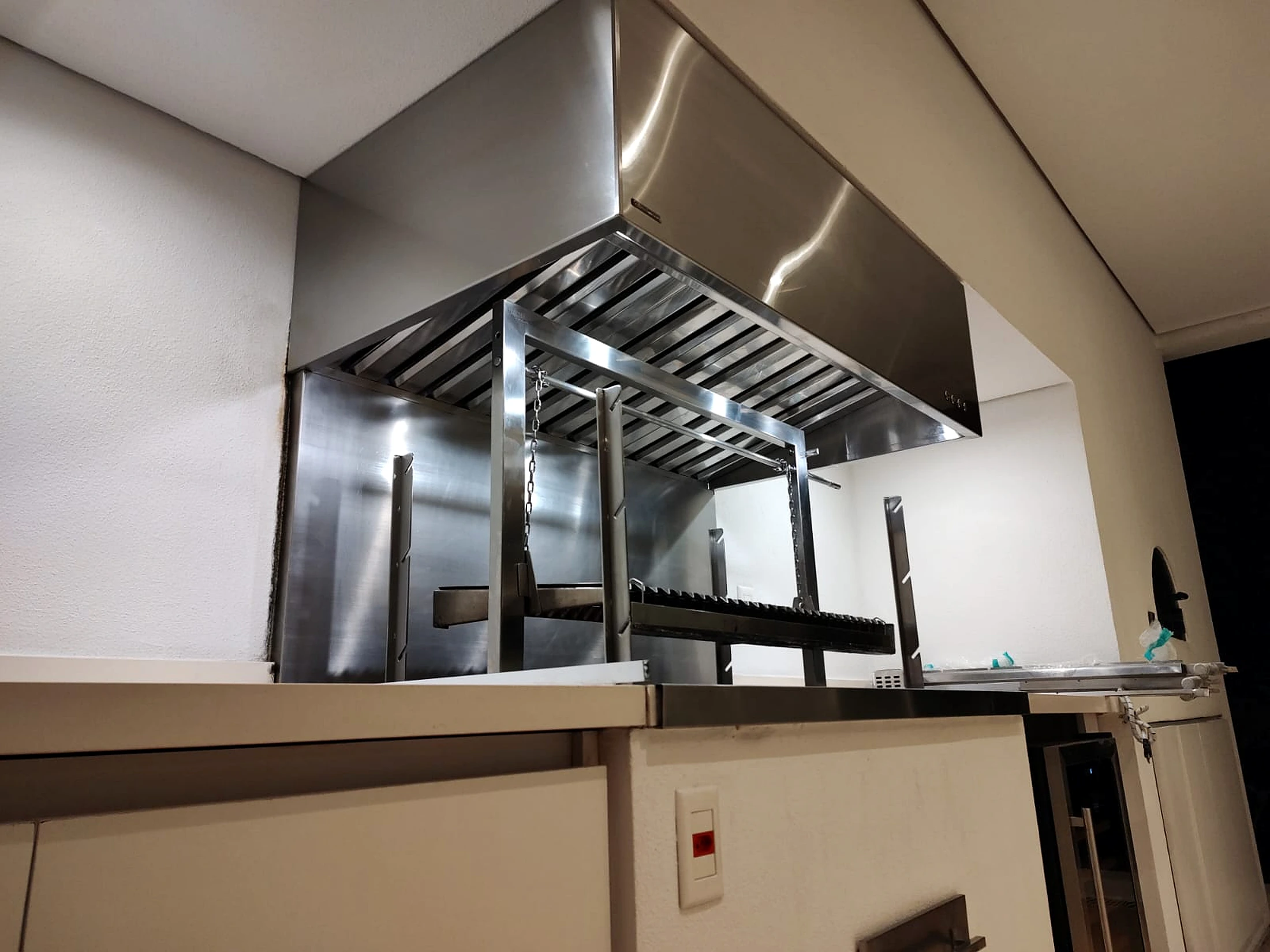 Coifa em aço inox instalada sobre churrasqueira gourmet