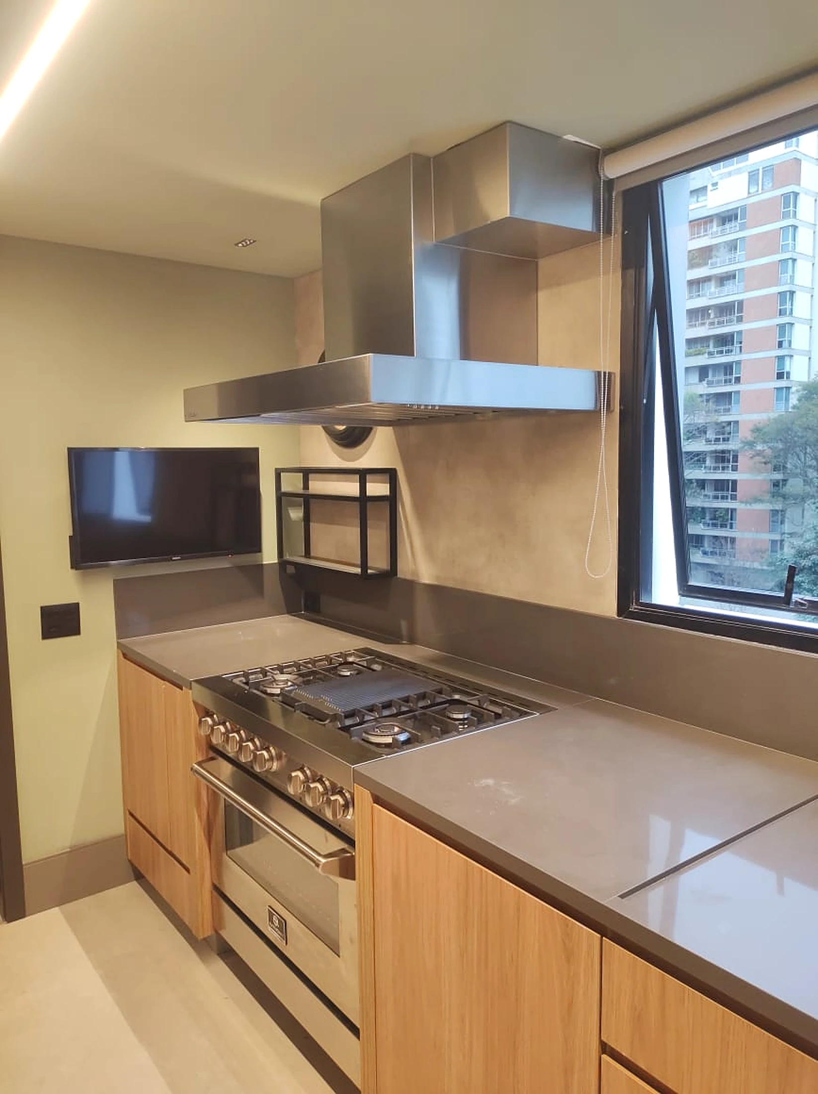 Coifa de parede em inox em cozinha residencial com fogão profissional